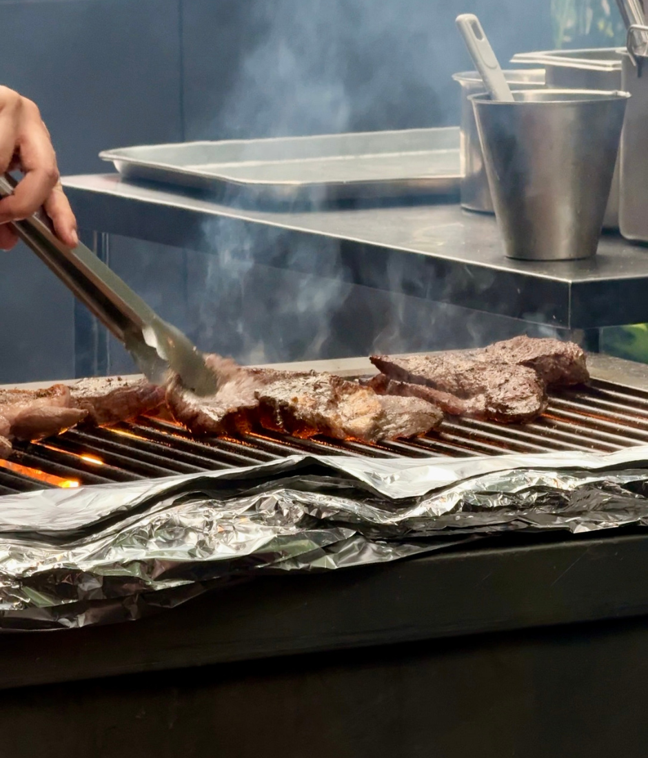 meat sizzling over a grill for The Curated Experience